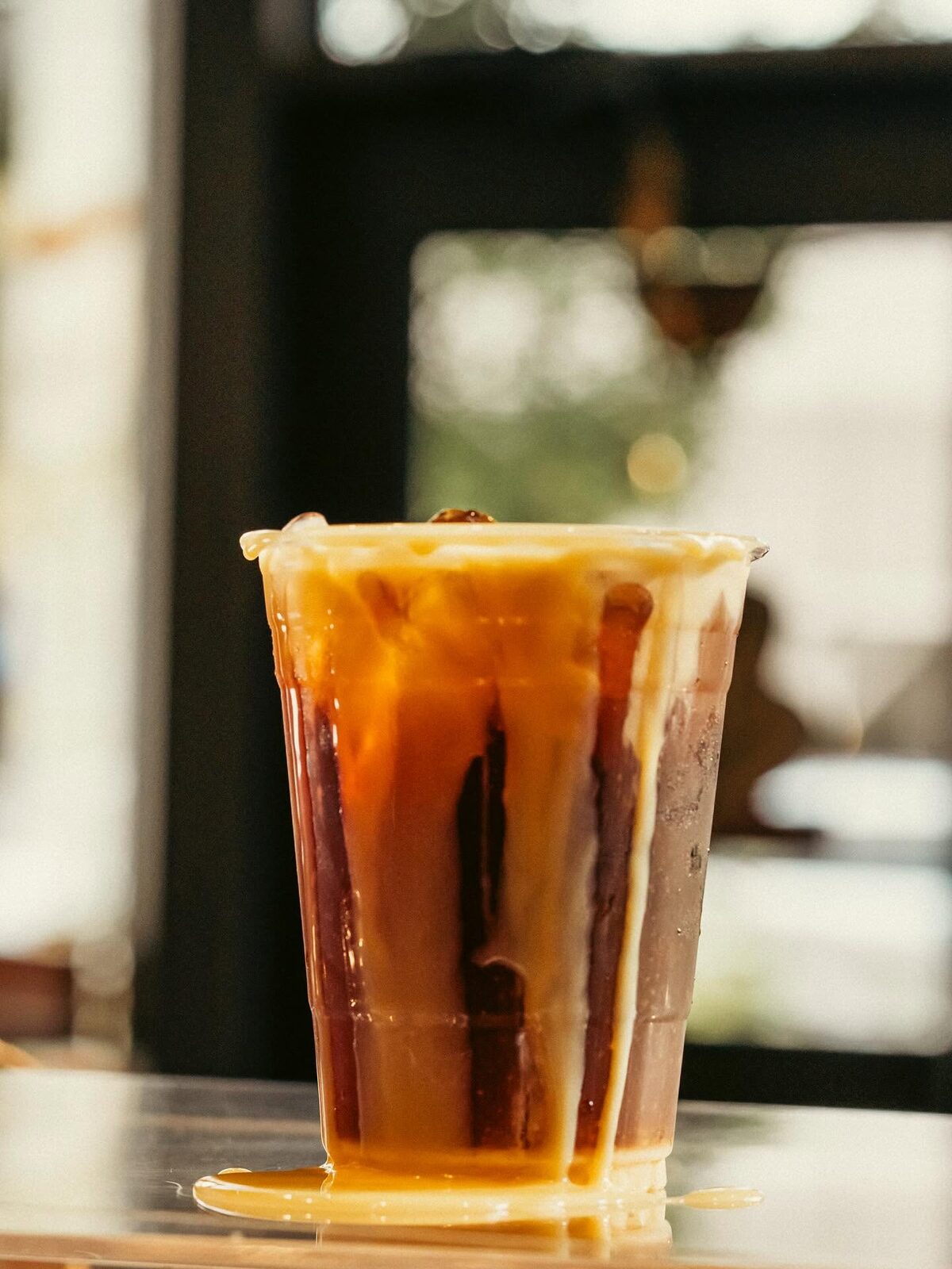 Iced coffee with sweet cream cascading down the cup